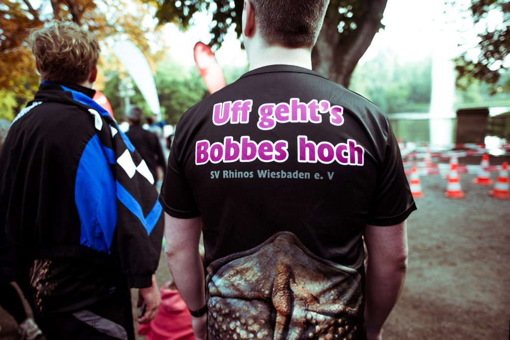 25h-9 Person mit T-Shirt "Uff geht's Bobbes hoch" in einer Gruppe.
