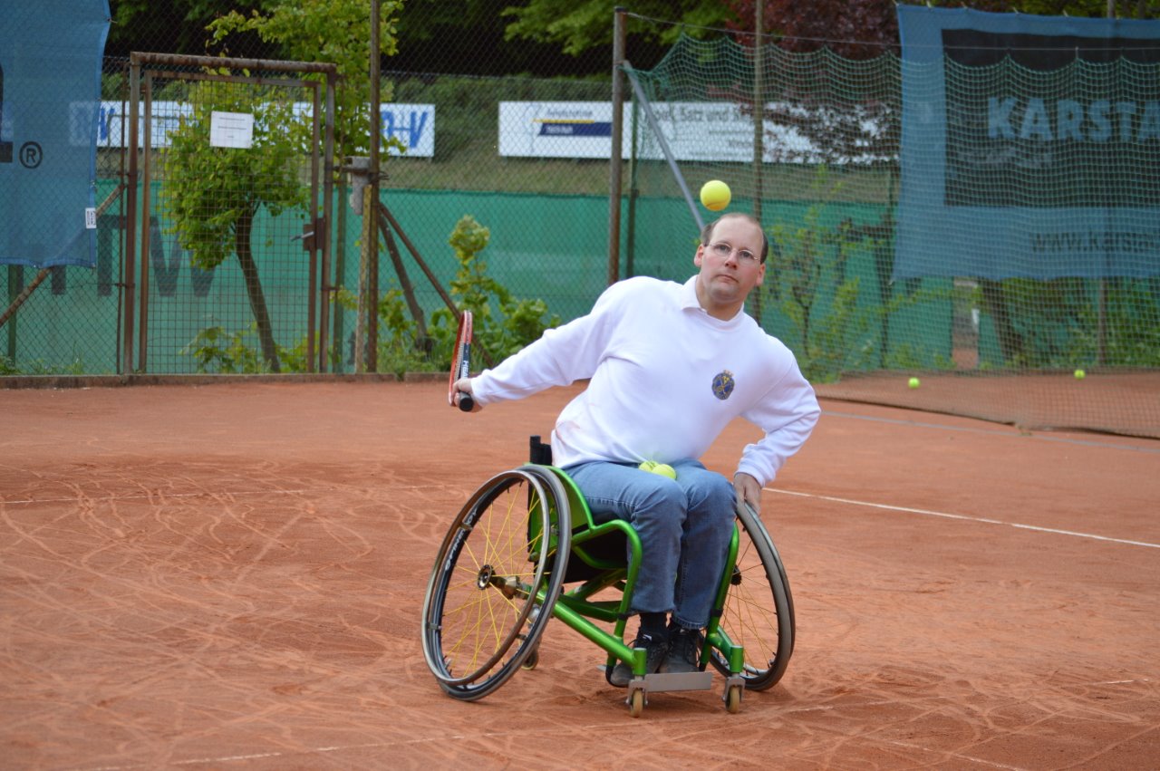 Rollstuhltennisspieler beim Schlag auf dem Platz.