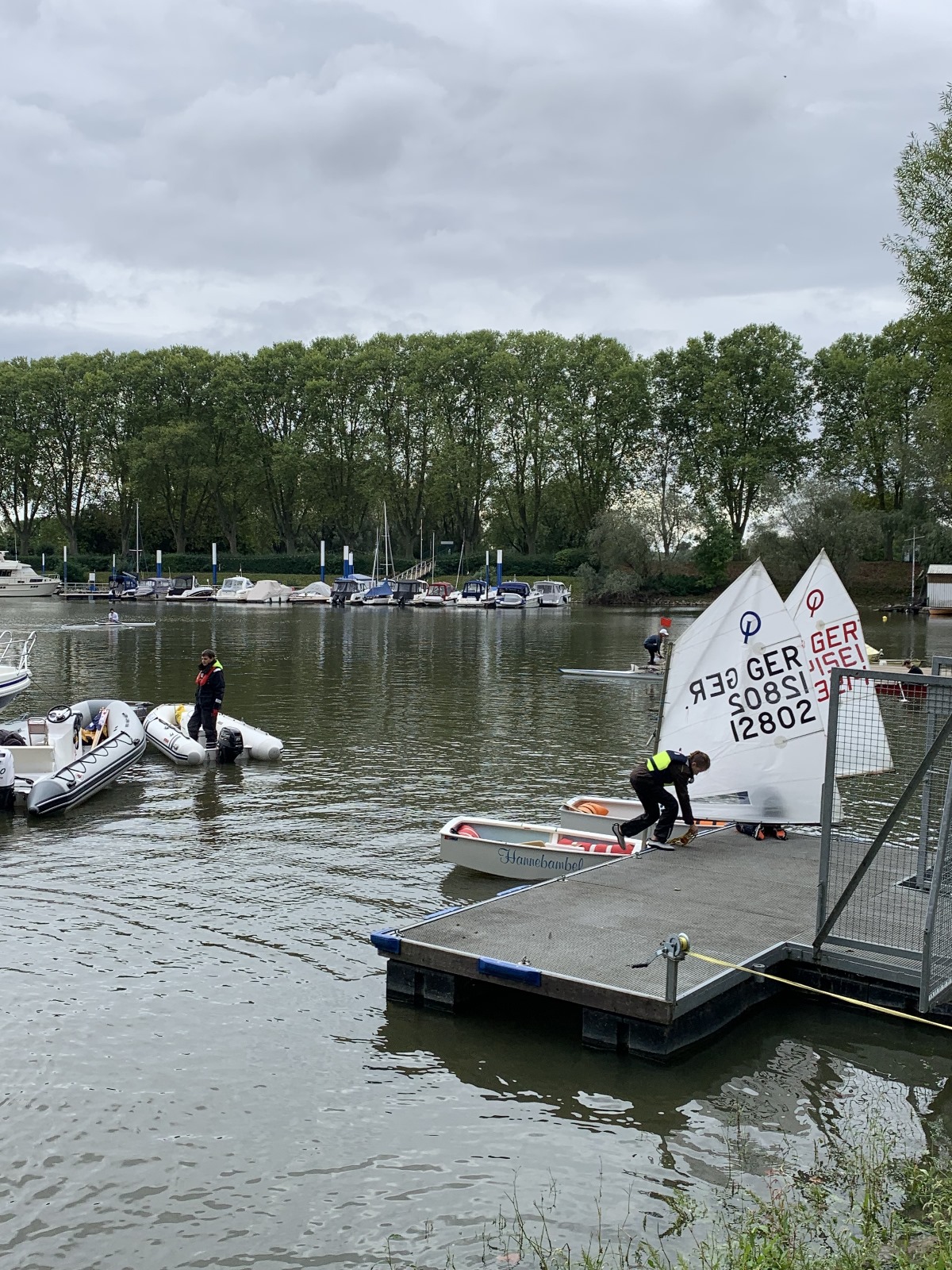 Segler beim Vorbereiten eines Bootes am Steg, Boote im Hintergrund.