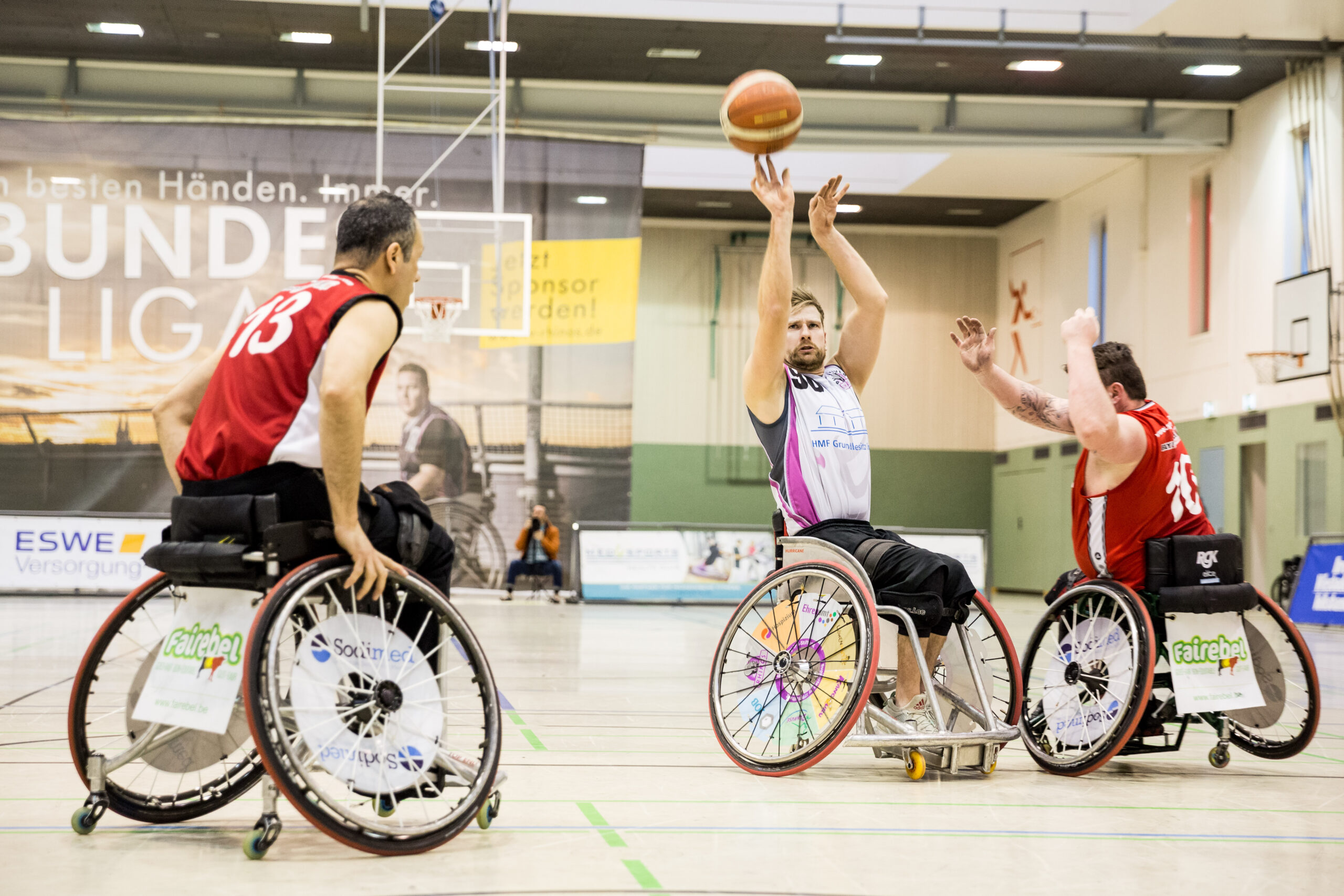 Rhinos-RollerBulls2 Rollstuhlbasketballer beim Wurf in der Halle, zwei Gegner versuchen zu blocken.
