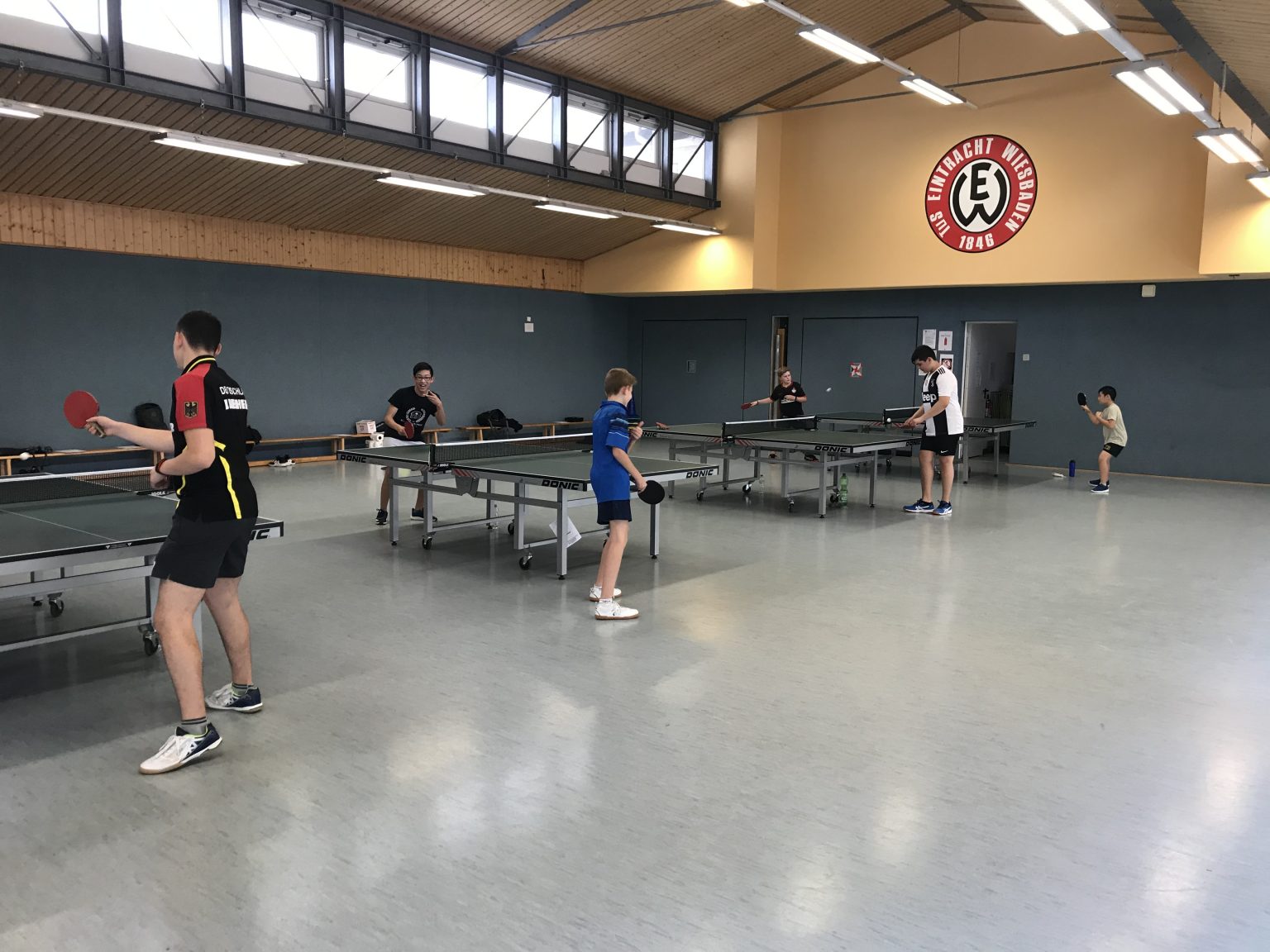 Bild_Eintracht-wiesbaden-tischtennistrainin Turnhalle des Sportvereins Eintracht Wiesbaden, Jugendmannschaft, die gerade an Tischtennisplatten trainiert