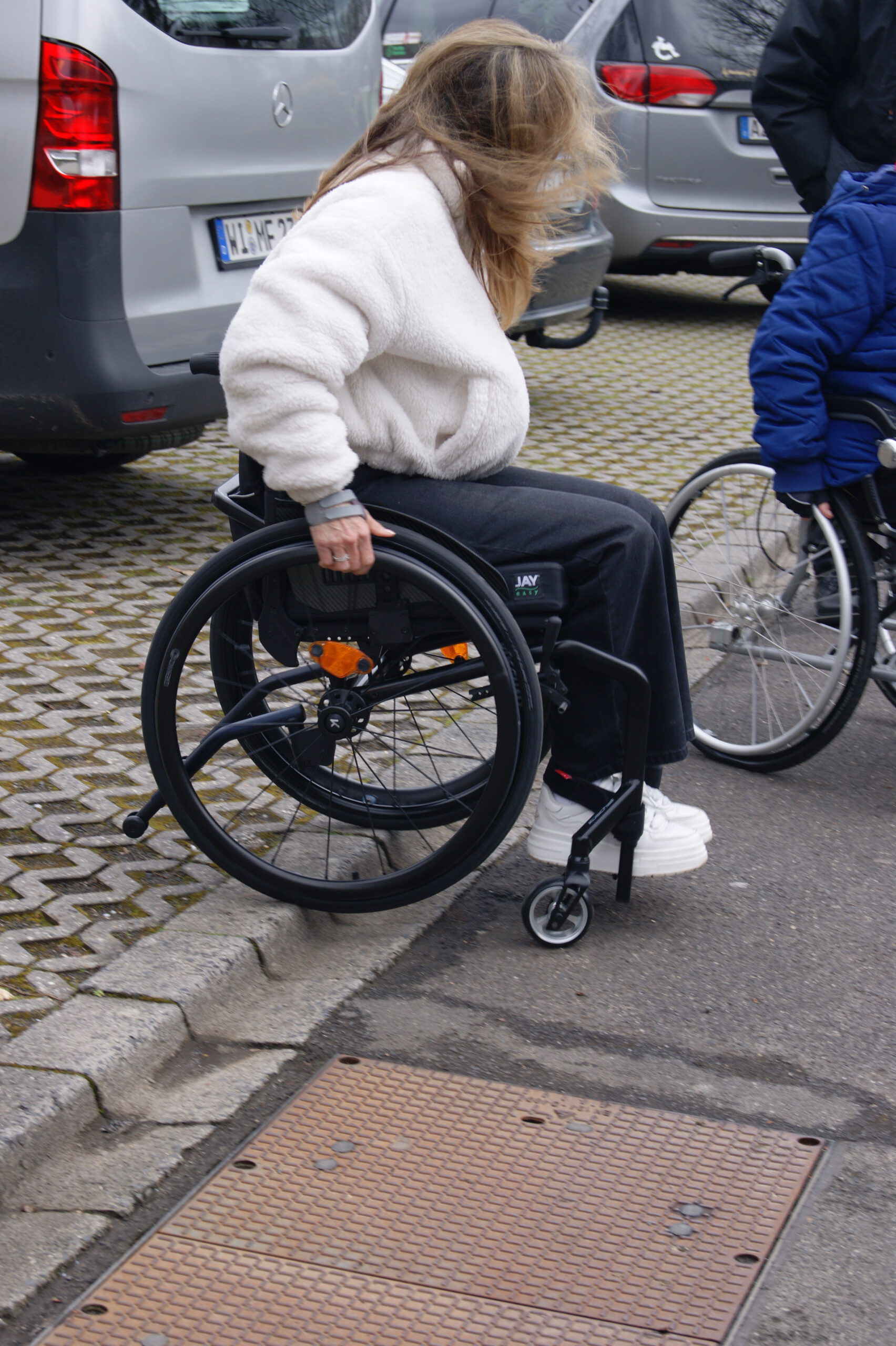 Rollifahrerin fährt an einen Bordstein