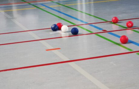 Boccia-Bälle in Rot, Blau und Weiß auf dem Spielfeld in einer Sporthalle nach einem Wurf