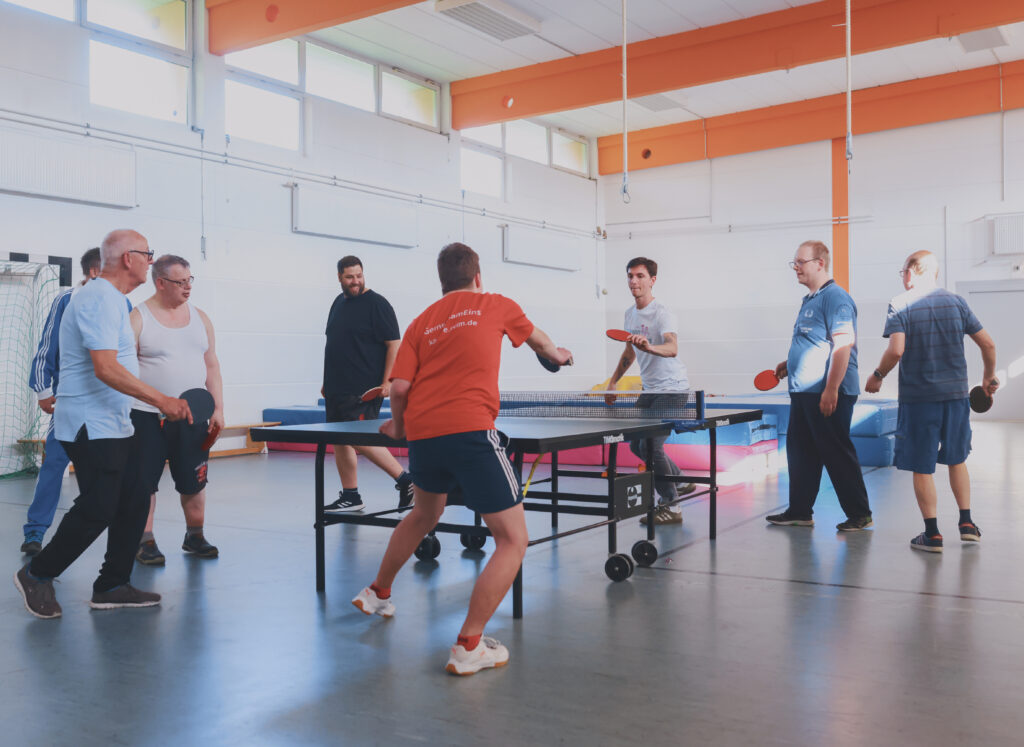 Team beim Tischtennis spielem im Rundlauf um eine Platte