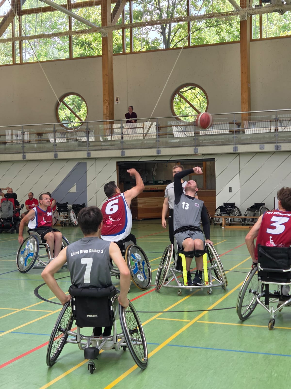 Spielszene Rollstuhlbasketball: Ein Rhinos-Spieler mit Nummer 13 und ein Tübinger Spieler mit Nummer 6 kämpfen um den Ball, davor ein Rhine-River-Rhinos-2-Spieler mit Nummer 7.